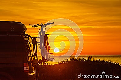 Camper with bicycles on rack camping on beach at sunrise Stock Photo