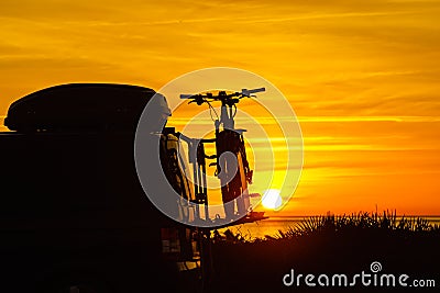 Camper with bicycles on rack camping on beach at sunrise Stock Photo