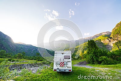 Camper van in the mountains, the Alps, Piedmont, Italy. Sunset dramatic sky and clouds, unique highlands and rocky mountains Stock Photo