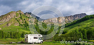 Camper van in the mountains, the Alps, Piedmont, Italy. Sunset dramatic sky and clouds, unique highlands and rocky mountains Stock Photo