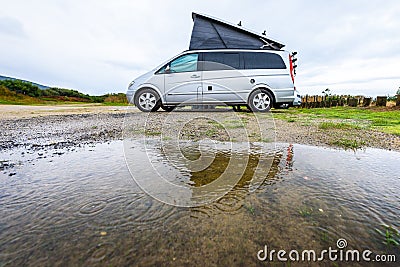 Campervan or motorhome camping on rainy day with rain puddles Stock Photo