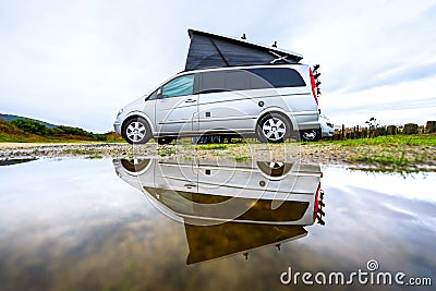 Campervan or motorhome camping on rainy day with rain puddles Stock Photo