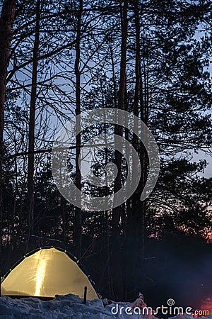 Campfire burns in the snow in the forest hill, on a background of snow covered trees and mountains campfire burning in cold winter Stock Photo