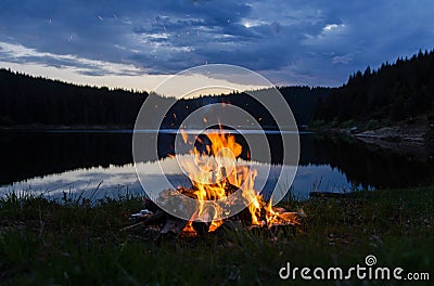 Campfire after sunset in the mountains next to a lake Stock Photo