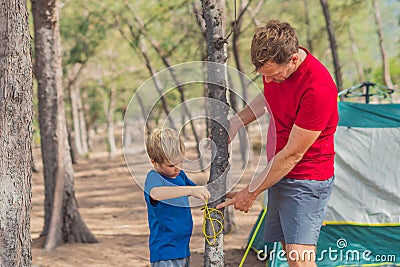 Camping people tourists putting up setting up green grey campsite summer forest near lazur sea. Natural wild live Stock Photo