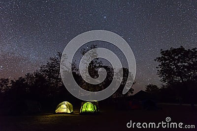 Camping tent glows under a night sky full of stars Stock Photo