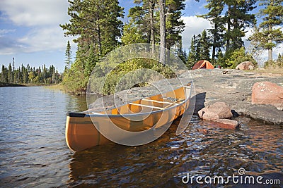 Campsite and canoe on rocky shore of lake Stock Photo