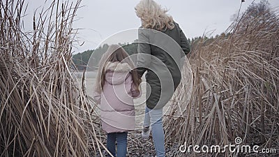Caméra après une femme et une fille caucasiennes adultes marchant jusqu'au lac ou à la rivière à travers des buissons Belle mère clips vidéos Caméra après une femme et une fille caucasiennes adultes marchant jusqu'au lac ou à la rivière à travers des buissons Belle mère clips vidéos