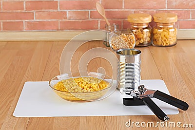 Can opener and bowl of canned corn Stock Photo