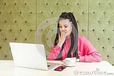 Can`t believe! Portrait of emotional shocked young woman with black dreadlocks hairstyle are sitting in cafe, reading news with Stock Photo