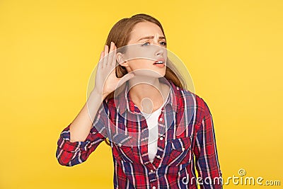 Can`t hear you! Portrait of attentive ginger girl in checkered shirt holding hand near ear trying to listen quiet conversation Stock Photo