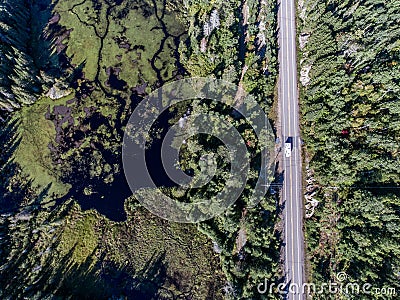 Beautiful Canada camper bus driving on road endless pine tree forest with lakes moor land aerial view travel background Stock Photo