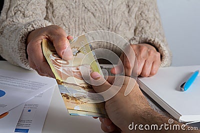 Canadian currency. Dollars. Old person delivering large amount o Editorial Stock Photo