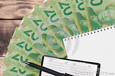 20 Canadian dollars bills fan and notepad with contact book and black pen. Concept of financial planning and business strategy Editorial Stock Photo