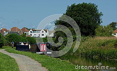 Canal boat owners enjoing summer sun as a cyclist passes by Editorial Stock Photo