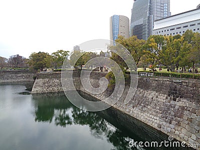 Canal with granite stone walls, greenery, building with cloudy sky, Osaka 2016 Editorial Stock Photo