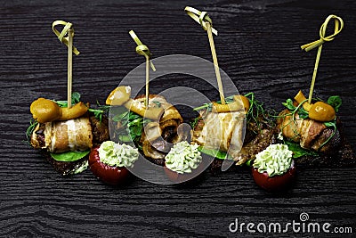 Canape, bread with bacon, tomatoes with cream pesto, honey agaric on wooden table, holiday appetizing Stock Photo