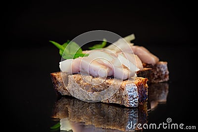 canape of pieces of salted herring with onions on a fresh dark piece of bread. Stock Photo