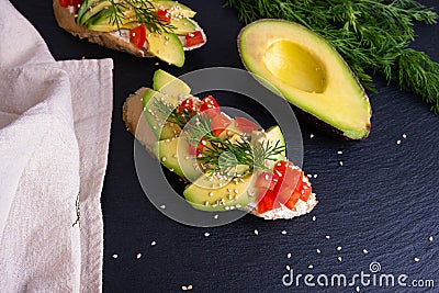 Canape - slices of crispy baguette with slices of ripe avocado and slices of juicy tomato, sprinkled with sesame seeds and Stock Photo