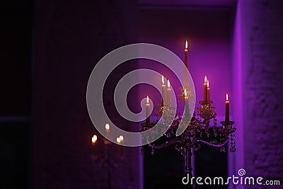 Candelabra with candles in purple backlit background Stock Photo