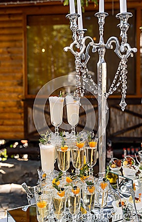 Candelstick and three vertical lines of crystal champagne glasses. Rich and fashionable decoration. Closeup. Stock Photo