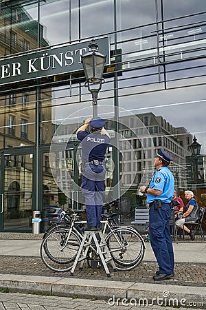 German Police or Polizei attaching no parking notice on a lamp pole near the US Embassy in Berlin, Germany Editorial Stock Photo