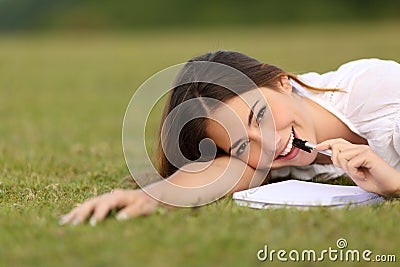 Candid happy woman lying on the grass writing Stock Photo