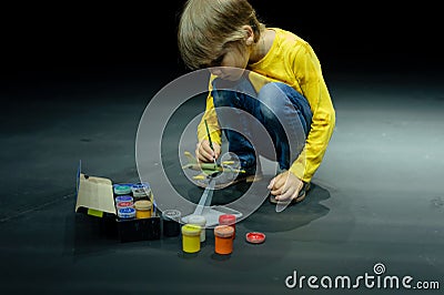 candid little six year old kid boy painting or colorize or colour model airplane with gouache paints Stock Photo