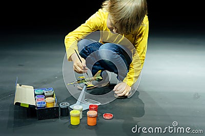 candid little six year old kid boy painting or colorize or colour model airplane with gouache paints Stock Photo