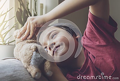 Candid short cheerful kid lying head down on sofa playing with dog toy, Child boy with haapy face playing with his soft toy or Stock Photo
