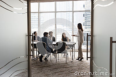 Candid shot through doorway of diverse business team discussing teamwork Stock Photo