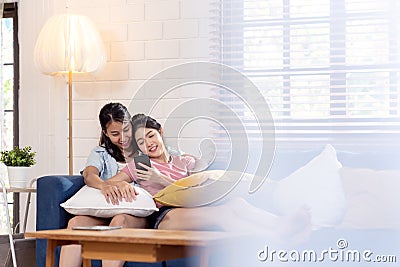 Candid of young attractive happy asian lesbian couple enjoy holiday weekend sitting on couch in living room at home feeling relax Stock Photo