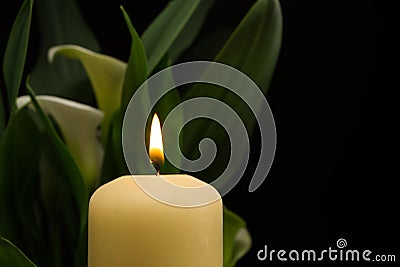 Candle burning flame in the darkness and arum lilies Stock Photo