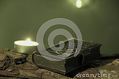 candle burns on tree bark on candle burning day with bookplate in leather binding Stock Photo