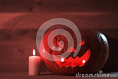 Candle and a creepy smiling Halloween pumpkin on a wooden table Stock Photo