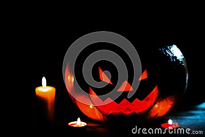 Candle and a creepy smiling Halloween pumpkin on a wooden table Stock Photo