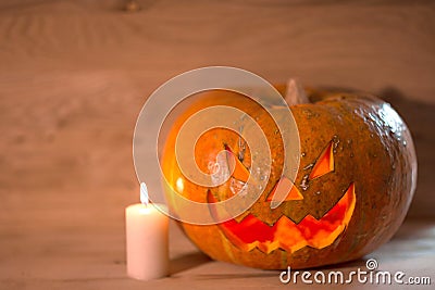 Candle and a creepy smiling Halloween pumpkin on a wooden table Stock Photo