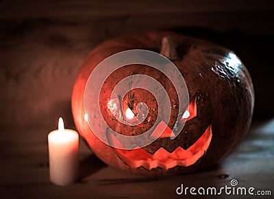 Candle and a creepy smiling Halloween pumpkin on a wooden table Stock Photo