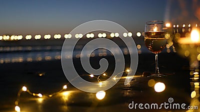 Candle flame lights in glass, romantic beach date by ocean waves, summer sea. Candlelight on sand. Stock Photo