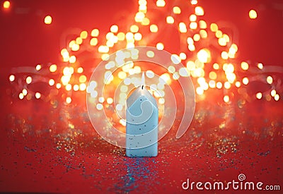 Candle with golden bokeh on red background. Stock Photo