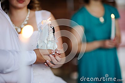 Candle in the hands of the newlyweds. Wedding Stock Photo