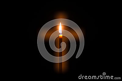 Candle is glowing through hole in shape of Christian cross Stock Photo