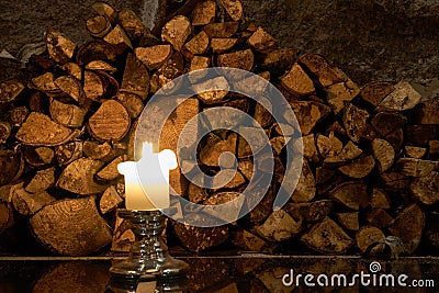 Candle with logs on a background and reflection on a floor. Stock Photo