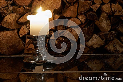 Candle with logs on a background and reflection on a floor. Stock Photo