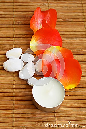 Candle, roses petals and stones on bamboo mat Stock Photo