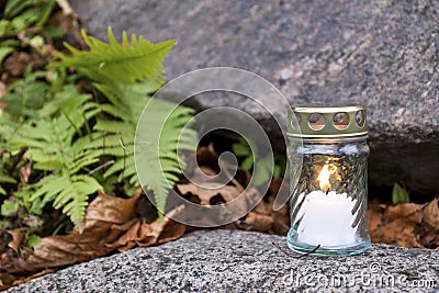 Candle standing on tombstone and burning Stock Photo