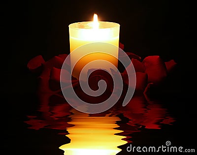 Candle surrounded by rose petals with reflection Stock Photo