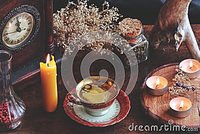 Candle wax poured into a red and gold vintage teacup as a divination form with a yellow burning candle standing next to it Stock Photo