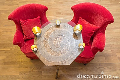 Candles on a antique side table with intarsia and red chair Stock Photo