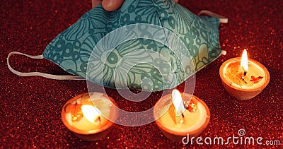 Candles and an ornamented face mask on the red surface; Divali festival in lockdown Stock Photo